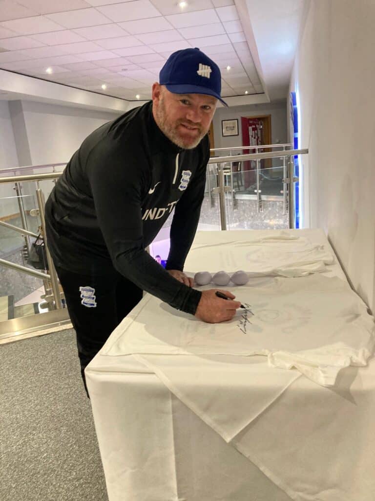 Wayne Rooney signing a shirt