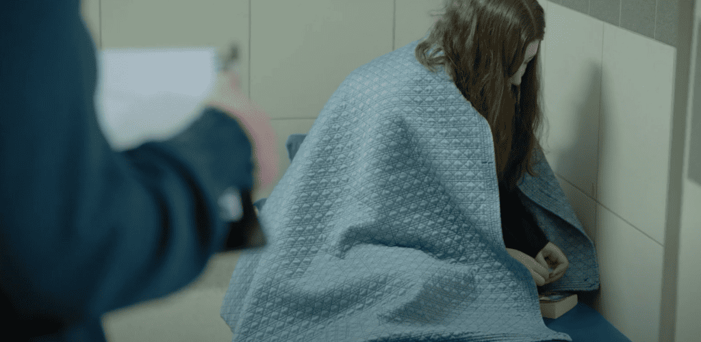 a young person in a cell with a blanket